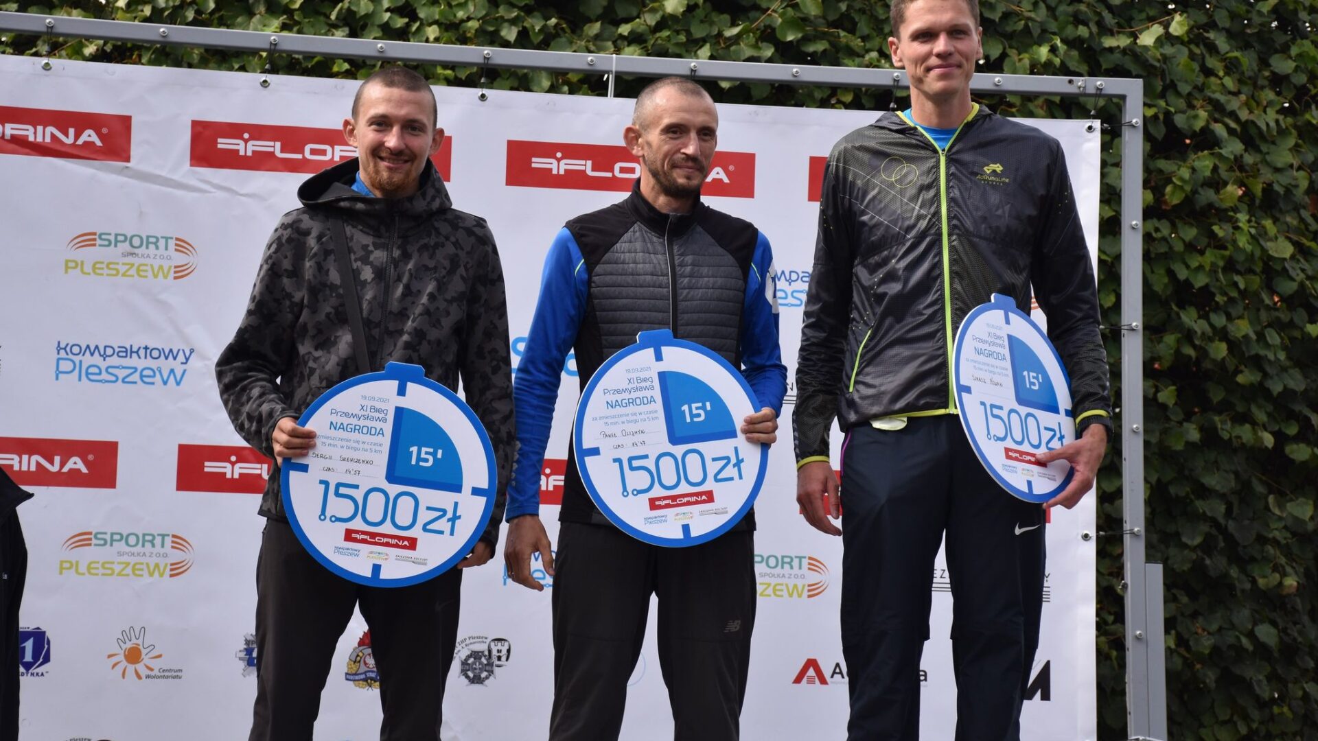 na pierwszym stopniu stoi trójka mężczyzn - zwycięzców Biegu Pzemysława na dystansie 5 km; w ręku trzymają nagrody