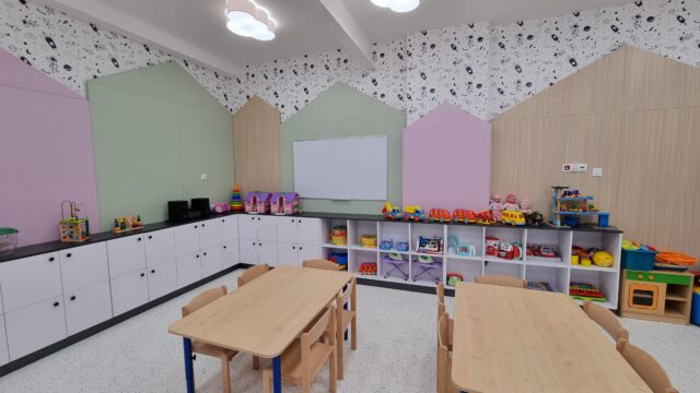 wnętrze sali przedszkola: meble, stoliki z krzesłami, szafki, zabawki na półkach