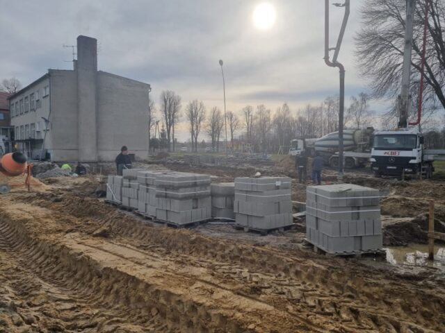Teren budowy, na którym widać materiały budowalne i część budynu szkoły w Lenartowicach
