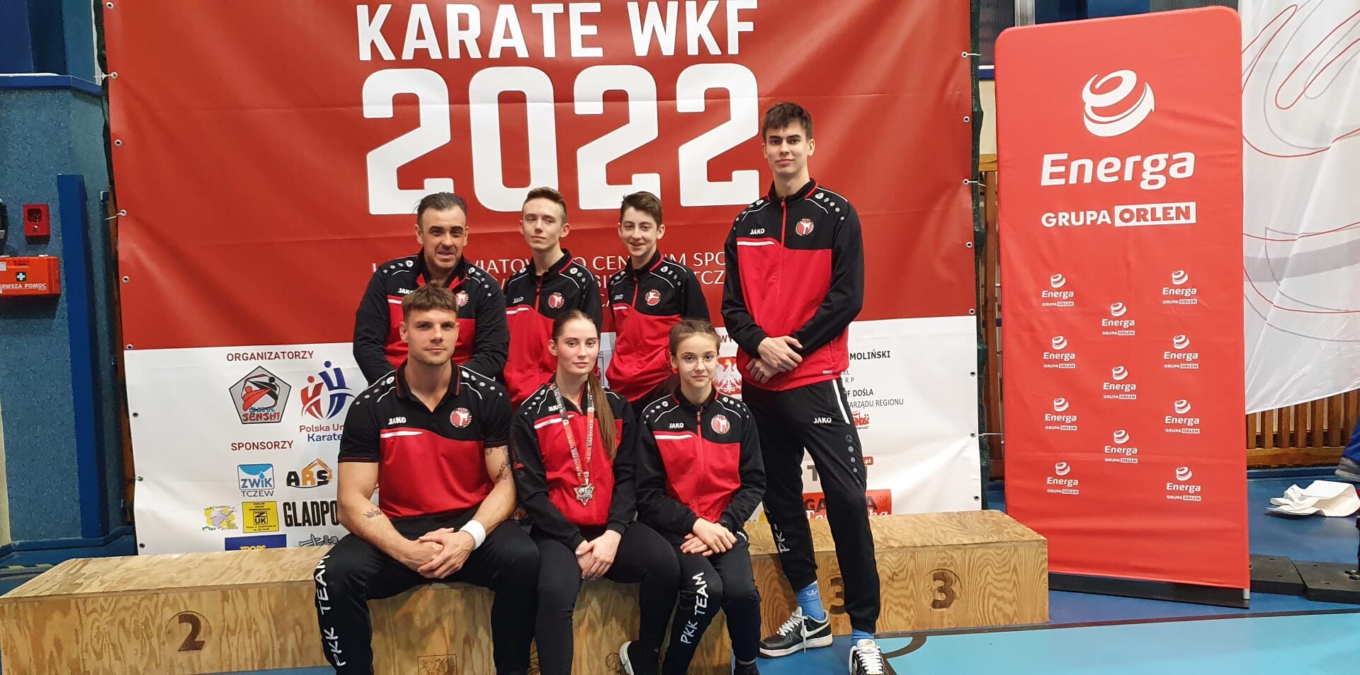 grupa 7 zawodników Pleszewskiego Klubu Karate pozująca do zdjęcia w sportowych strojach