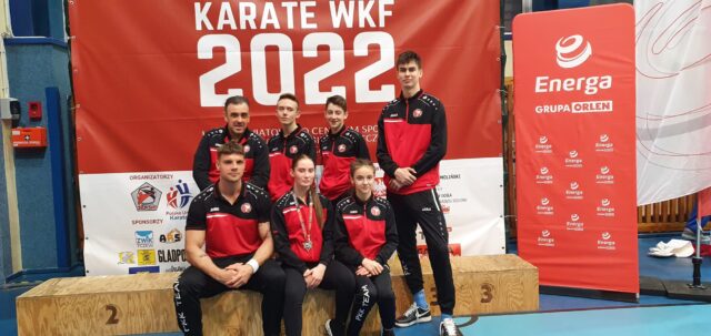 grupa 7 zawodników Pleszewskiego Klubu Karate pozująca do zdjęcia w sportowych strojach 