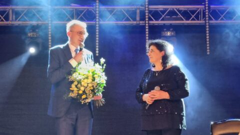 Burmistrz Miasta i Gminy Pleszew wręczajacy bukiet kwiatów Eleni występującej w Pleszewie z okazji Dnia Kobiet
