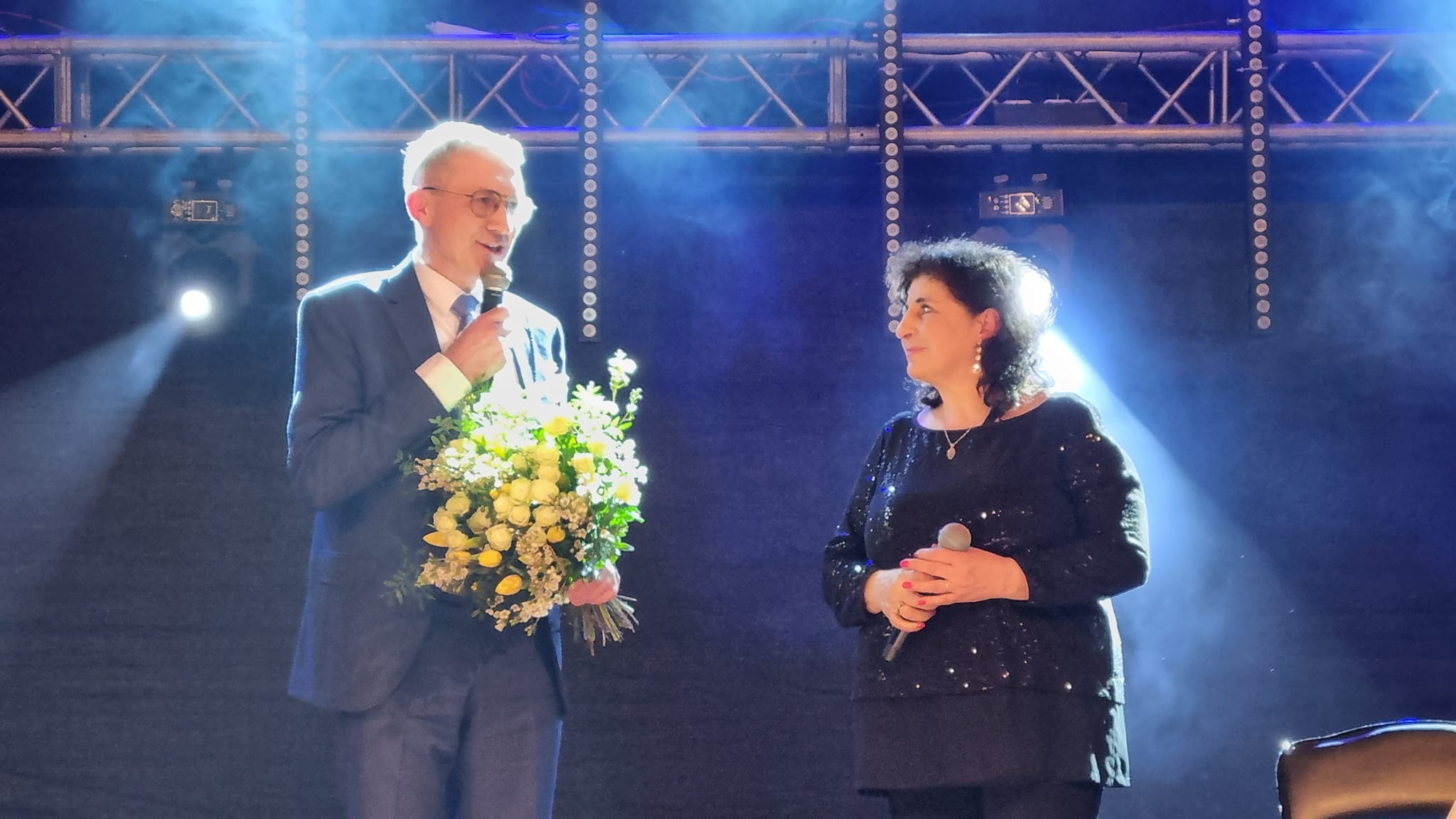Burmistrz Miasta i Gminy Pleszew wręczajacy bukiet kwiatów Eleni występującej w Pleszewie z okazji Dnia Kobiet