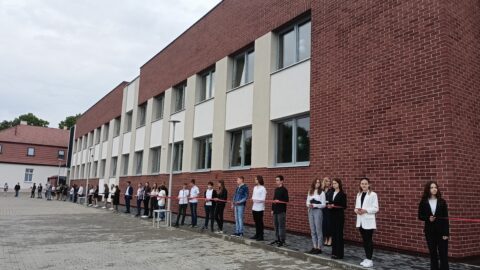 Uczniowie ze wstęgą opasającą całą szkołę w Lenartowicach podczas otwarcia po remoncie.