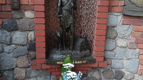 Kwiaty w barwach miasta złożone pod figurą patrona Pleszewa - św. Jana Chrzciciela na Murze Pamięci przy pleszewskiej farze.