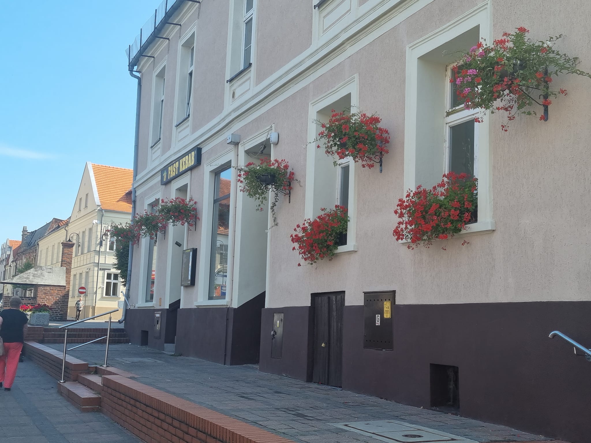 Pleszewski Rynek oraz wiszące donice z kwiatami zdobiące pleszewskie kamienice.