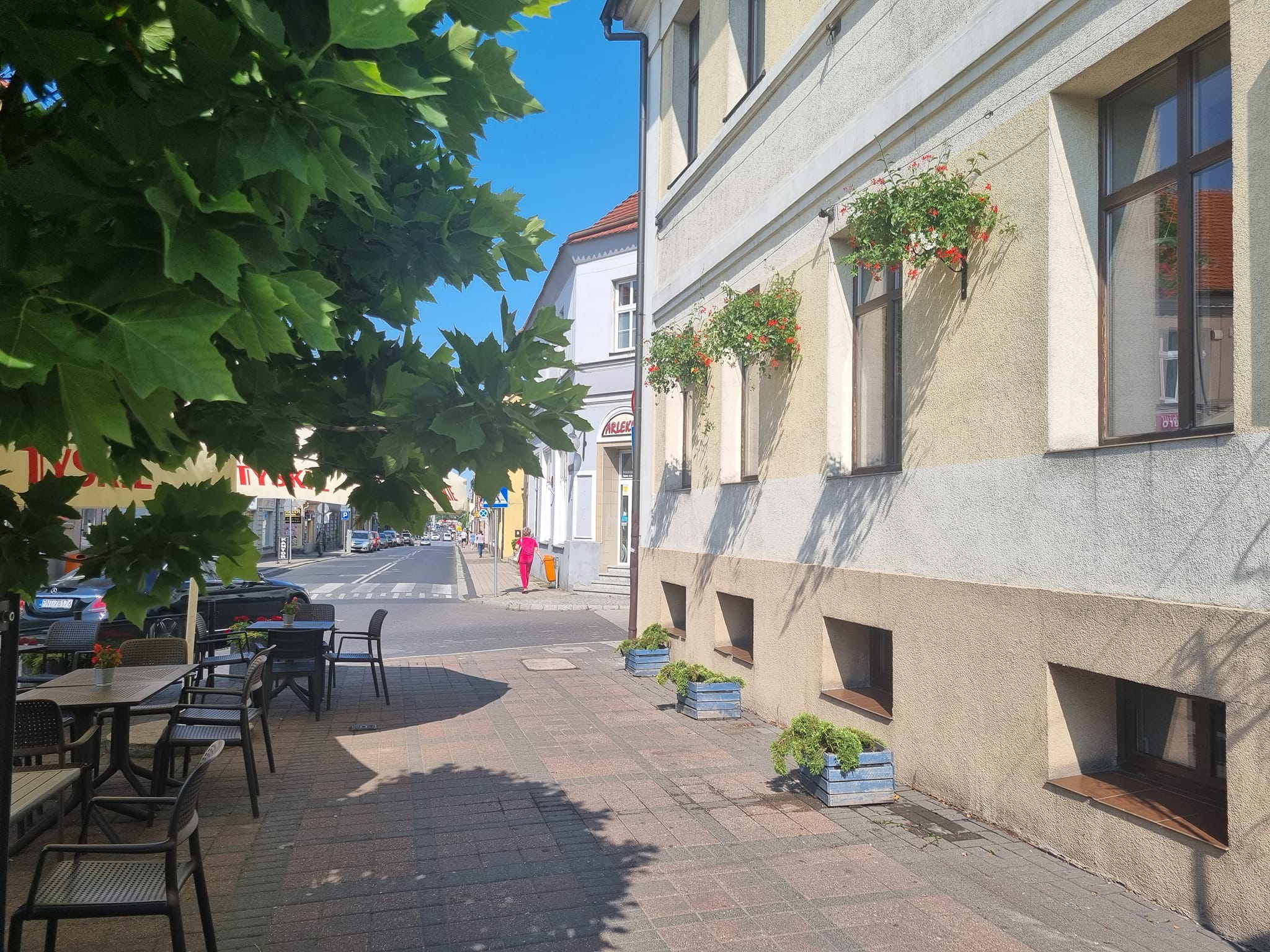 Pleszewski Rynek oraz wiszące donice z kwiatami zdobiące pleszewskie kamienice.