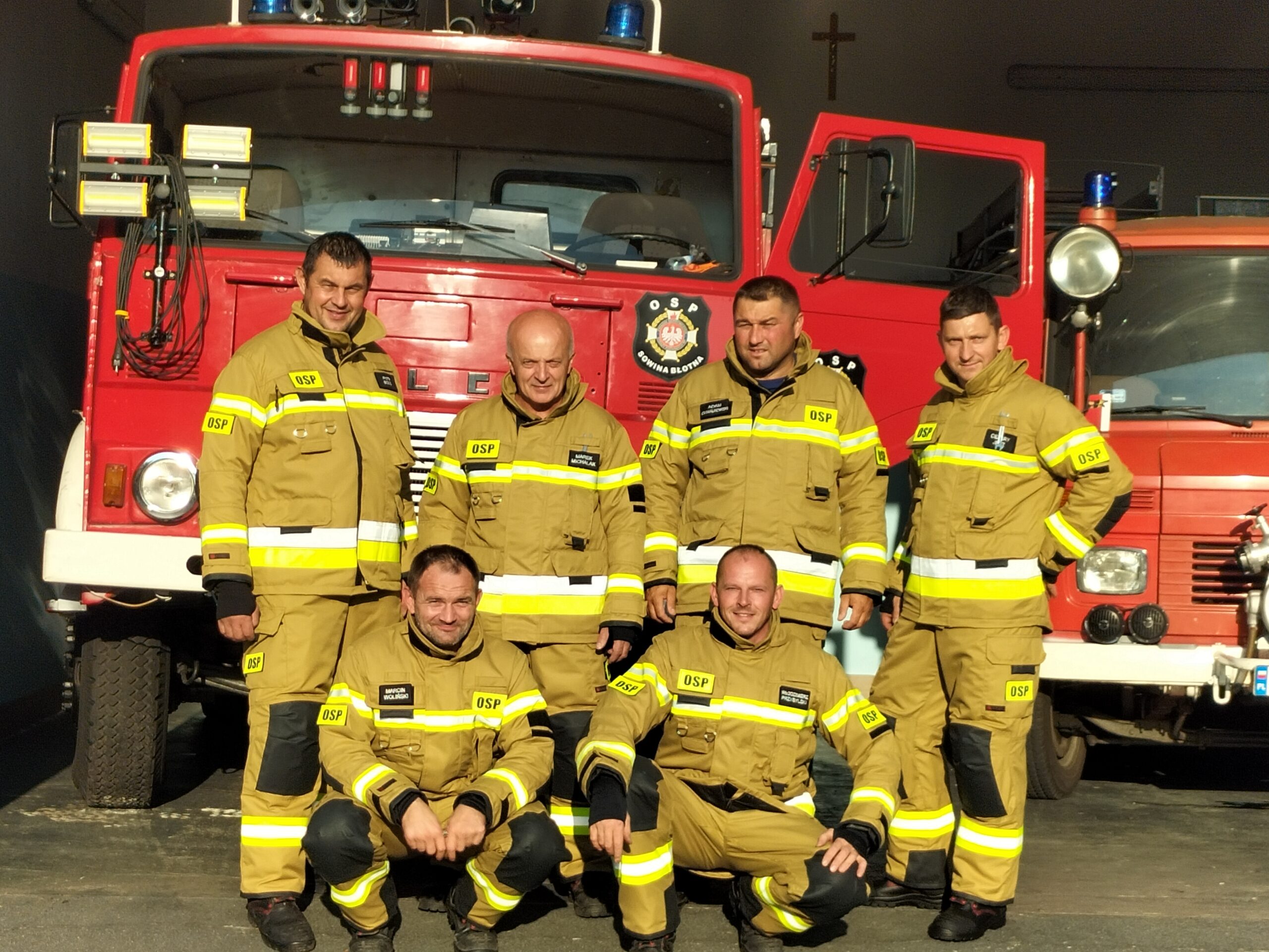 Strażacy z OSP Sowina Błotna w nowych strojach na tle wozu strażackiego.