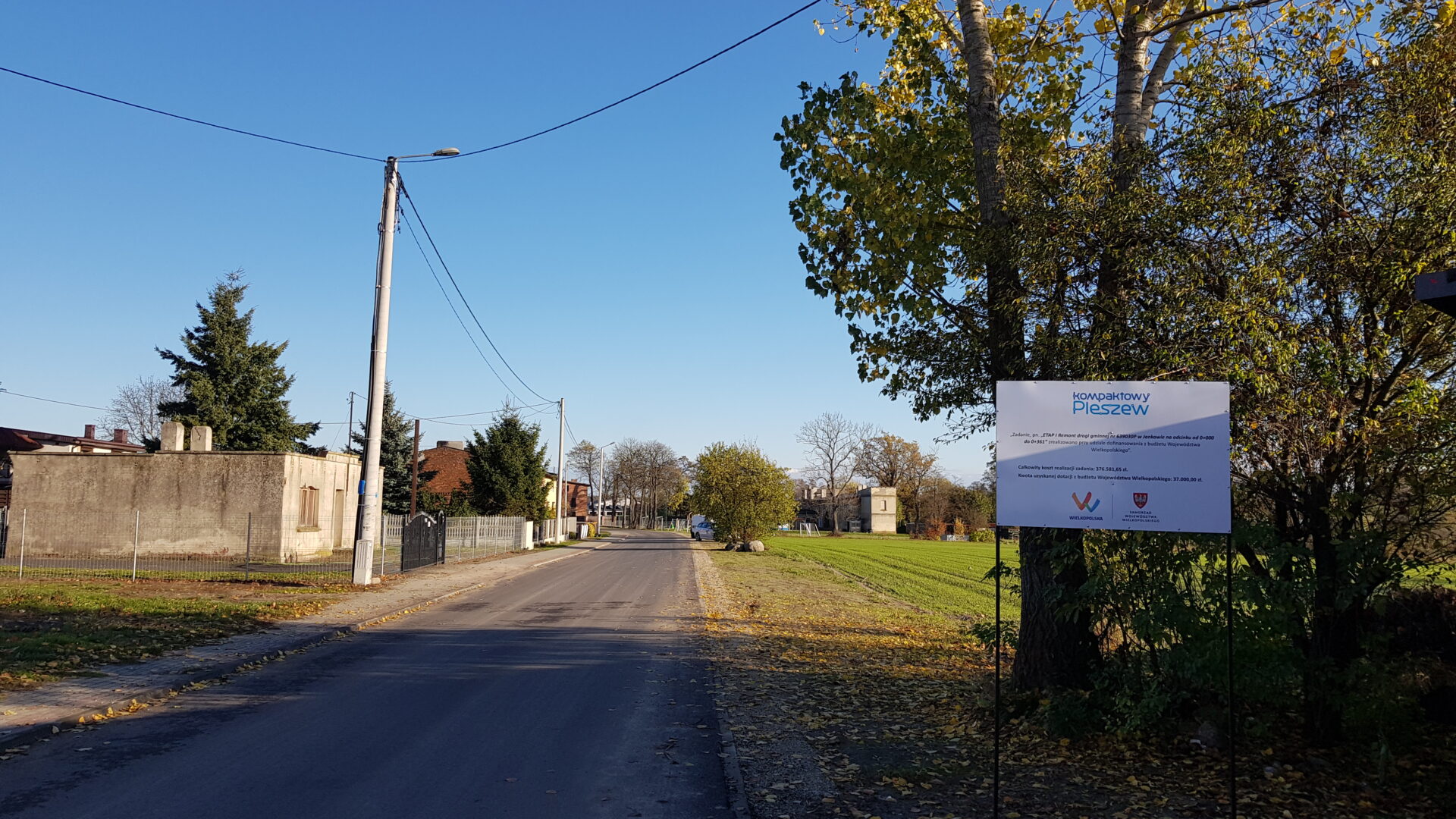 Wyremontowana droga w Jankowie w Gminie Pleszew i tablica przedstawiająca informacje o dofinansowaniu.