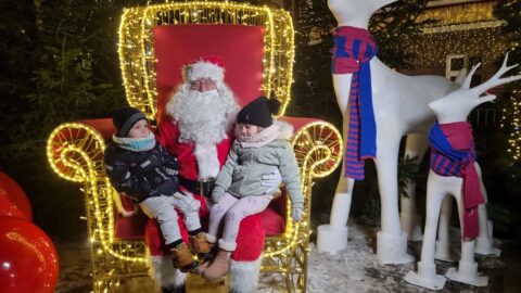 Święty Mikołaj z dziećmi na oświetlonym tronie
