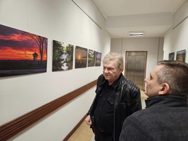 artyści oglądający swoje fotografie wiszące na korytarzach pleszewskiego ratusza.