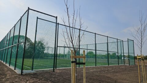 Nowe boisko w Taczanowie Drugim otoczone piłkochwytami oraz drzewa rosnące dookoła.