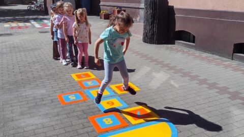 Dzieci grające w klasy na specjalnych grach podwórkowych pod przedszkolem.
