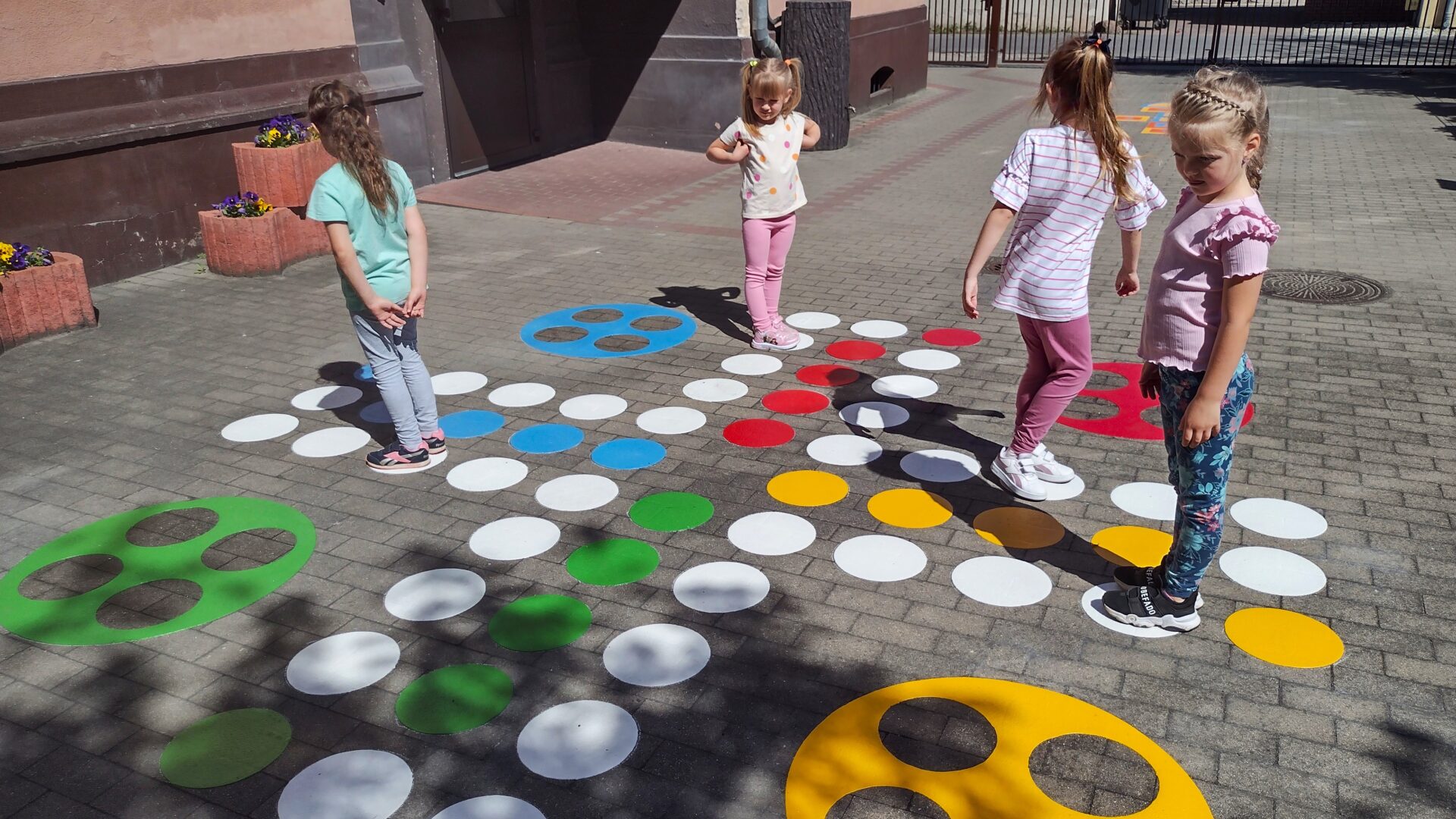 Dzieci grające na specjalnych grach podwórkowych pod przedszkolem.