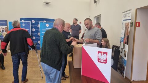 Ludzie wrzucający karty do głosowania do urny w czasie wyborów na sołtysów i przewodniczących osiedli MiG Pleszew.