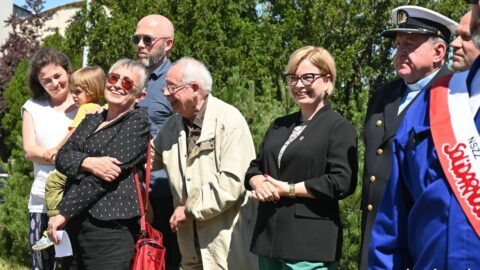 Uśmiechnięte osoby na tle zieleni zgromadzone na nadaniu imienia ronda im. Wojciecha Żychskiego w Gdyni.