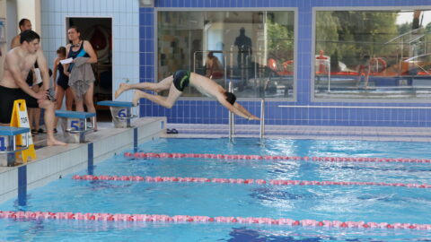 Osoba wskakująca do wody podczas pływania w ramach olimpiady sportowej.
