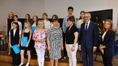 Uczniowie oraz nauczyciele ZSP nr 1 w Pleszewie z burmistrzami stojący na scenie po wręczeniu listów gratulacyjnych.