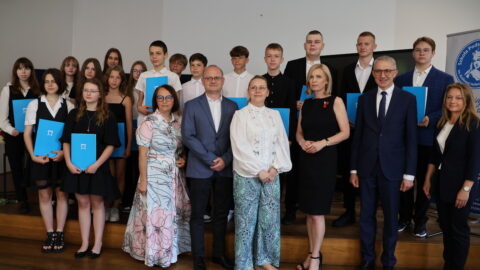Uczniowie oraz nauczyciele ZSP nr 3 w Pleszewie z burmistrzami stojący na scenie po wręczeniu listów gratulacyjnych.