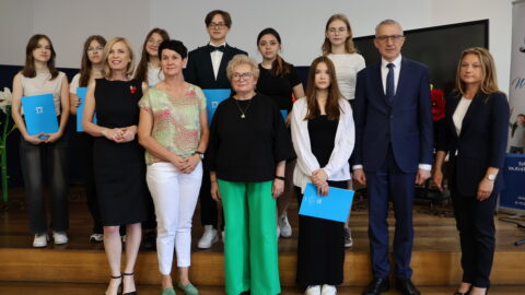 Uczniowie oraz nauczyciele ZSP w Kowalewie w Pleszewie z burmistrzami stojący na scenie po wręczeniu listów gratulacyjnych.