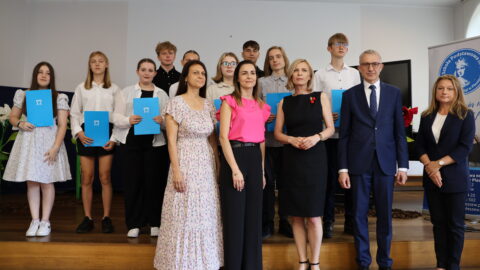 Uczniowie oraz nauczyciele ZSP nr 2 w Pleszewie z burmistrzami stojący na scenie po wręczeniu listów gratulacyjnych.