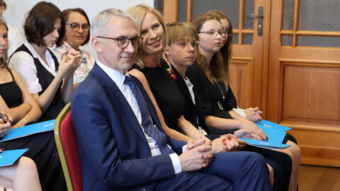 Burmistrz oraz jego zastępczyni i inne osoby siedzące na krzesłach w auli ZSP nr 2 w Pleszewie podczas uroczystości wręczenia listów gratulacyjnych