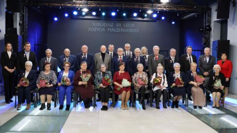 Kilkanaście par małżeńskich obchodzących Złote Gody pozujących do wspólnego zdjęcia.