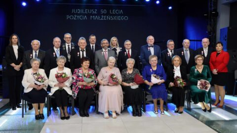 Kilkanaście par małżeńskich obchodzących Złote Gody pozujących do wspólnego zdjęcia.