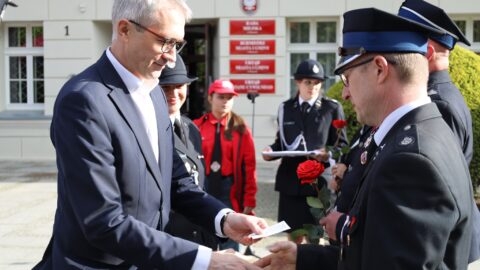 Burmistrz wręczający odznaki strażakom z okazji Dnia Strażaka przed pleszewskim ratuszem.