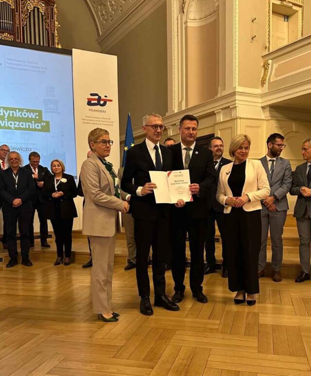 burmistrz MiG Pleszew odbierający nagrodę w auli UAM podczas konferencji.