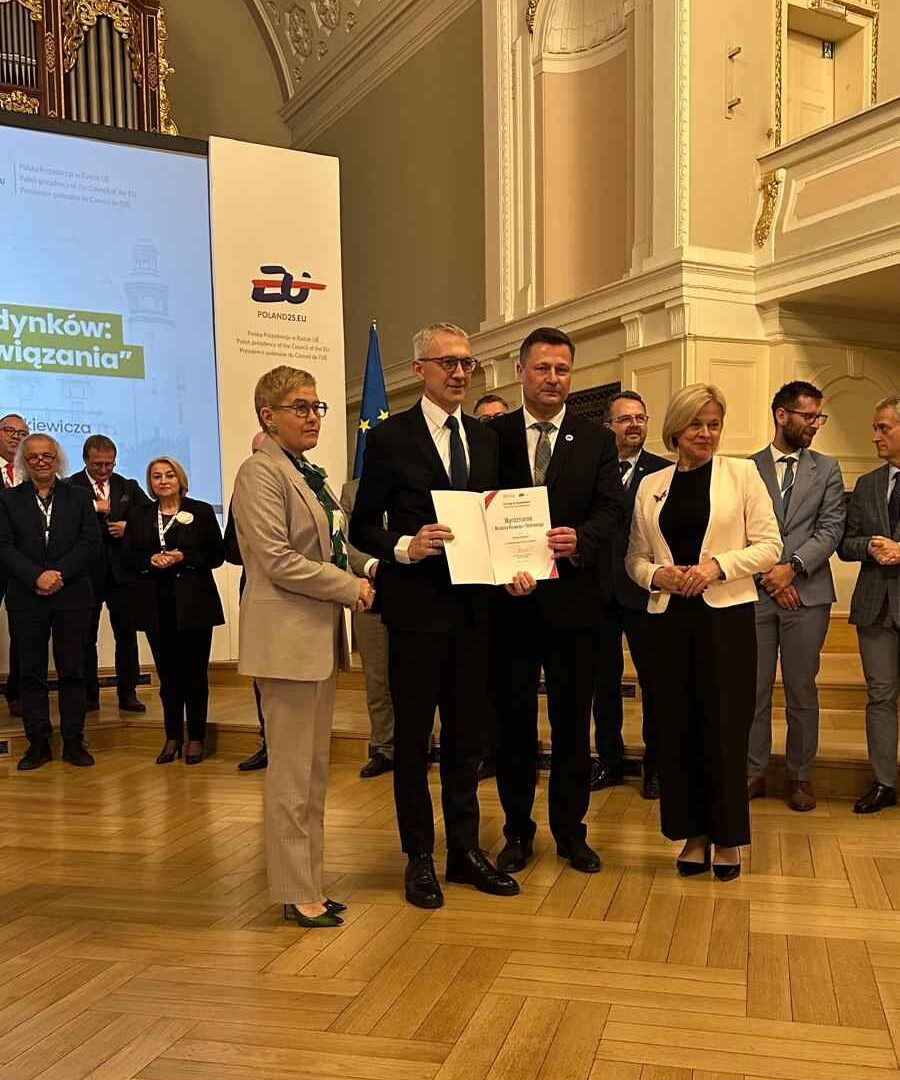burmistrz MiG Pleszew odbierający nagrodę w auli UAM podczas konferencji.