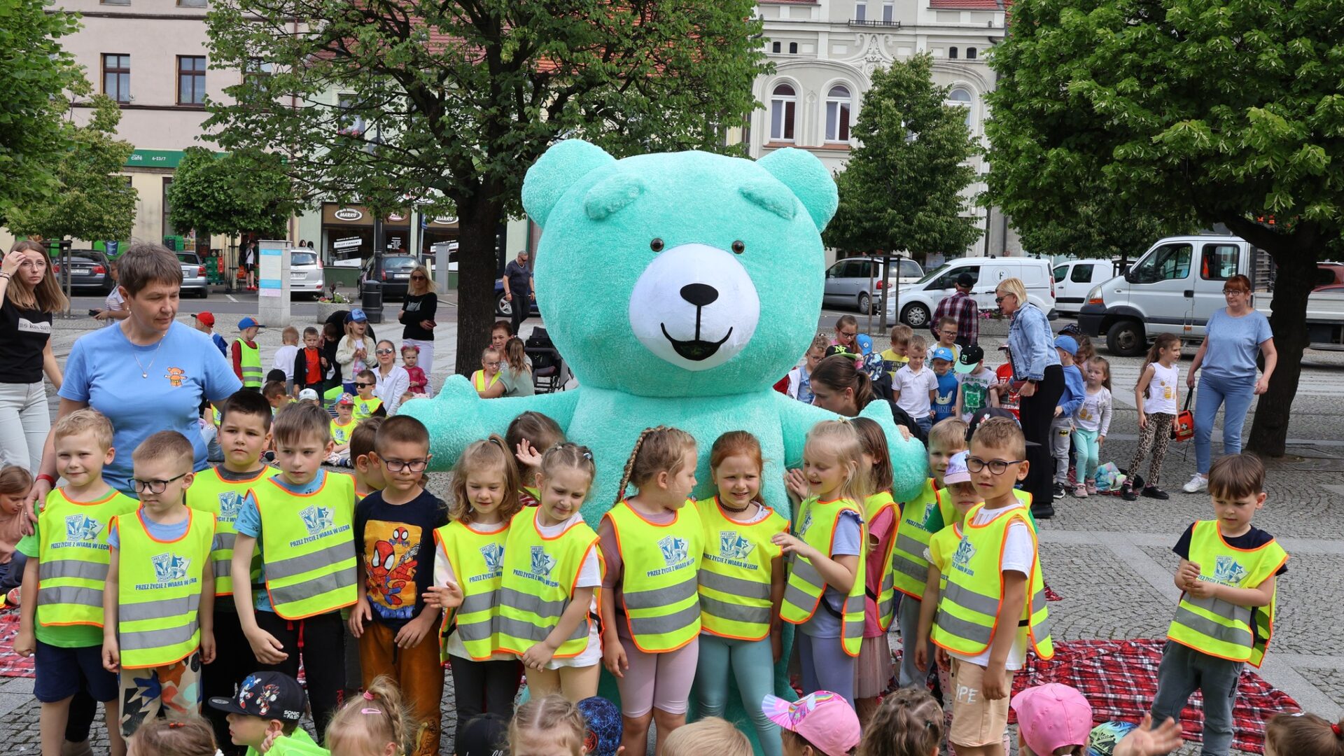 Dzieci z przedszkola stojące z wielkim pluszowym misiem