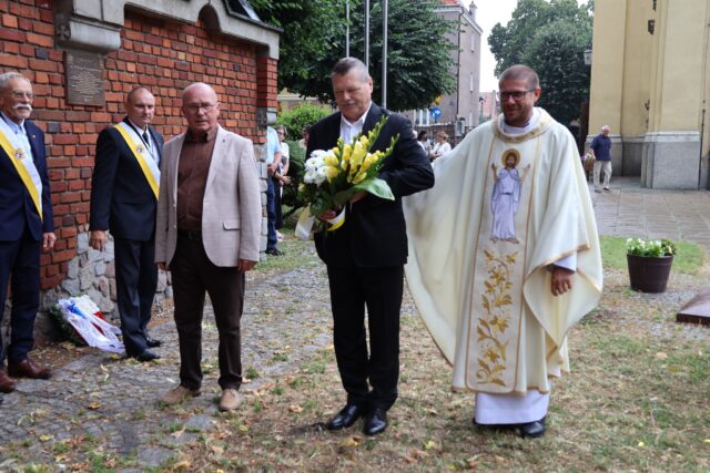 Delegacja składająca kwiaty pod figurą św. Jana Chrzciciela na Murze Pamięci w Pleszewie.