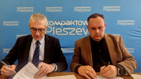 Dwaj mężczyźni podpisujący umowę przy biurku w ratuszu