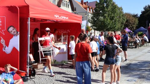 Uczestnicy biegu korzystający z oferty stoiska pod namiotem.