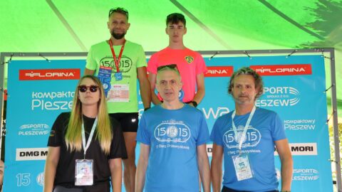 Mężczyźni na podium Biegu Przemysława w Pleszewie z wręczającymi nagrodę