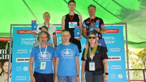 Mężczyźni na podium Biegu Przemysława w Pleszewie z wręczającymi nagrodę