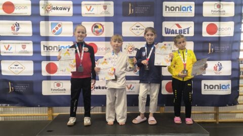 Dziewczynki na podium zawodów karate z medalami i dyplomami