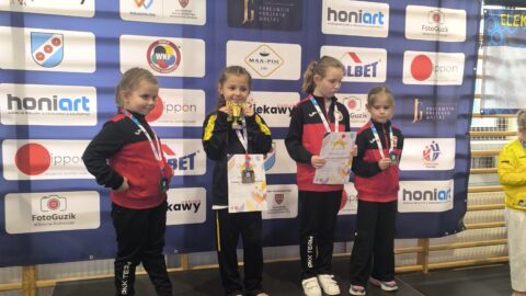 Dziewczynki na podium zawodów karate z medalami i dyplomami