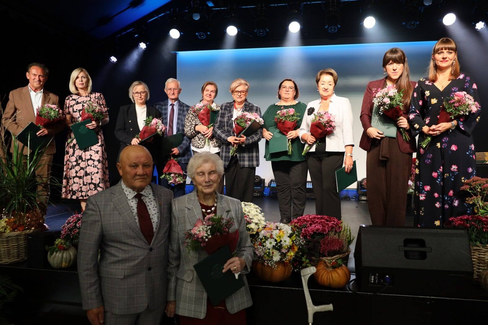 osoby stojące na scenie z wyróżnieniami z okazji 15-lecia Pleszewskiego UTW