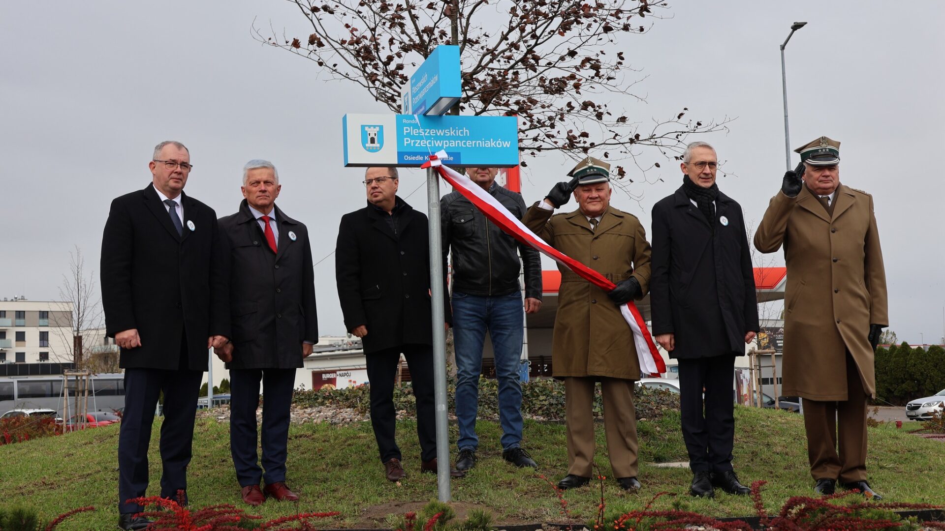 Władze oraz wojskowi odsłaniający tablicę z nową nazwą ronda w Pleszewie.