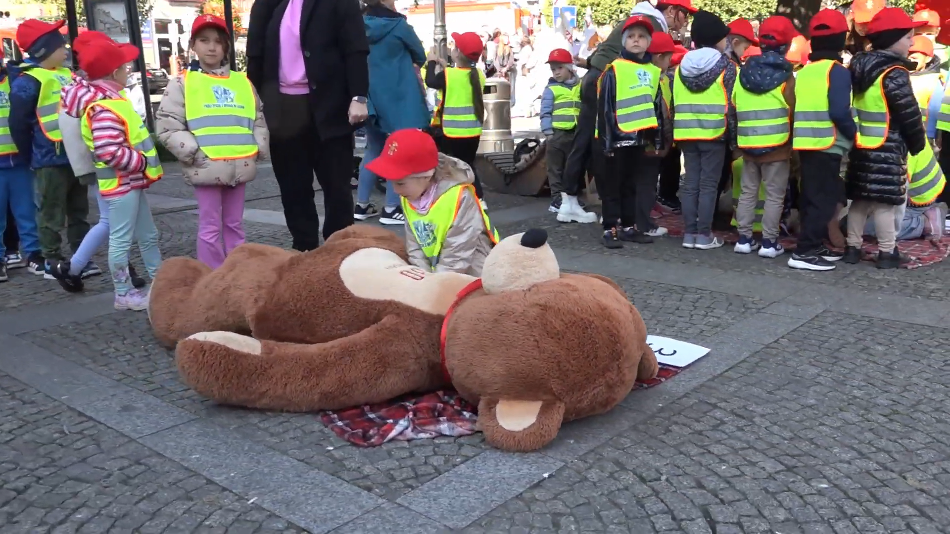 Okładka Flesza PPL październik 2025, któa przedstawia dzieci uczestniczące w akcji resuscytacji na pleszewskim rynku.