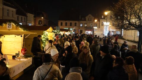 Tłumy ludzi przy świątecznych budkach na jarmarku na rynku.