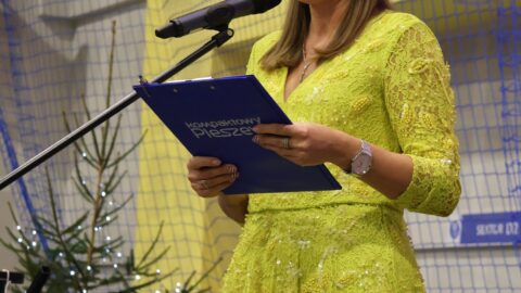 Prowadząca na scenie w hali sportowej podczas Wigilii dla Samotnych w Pleszewie.