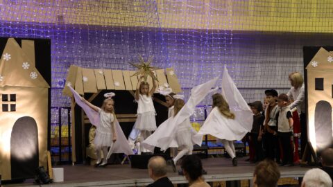 Przedszkolaki występujące na scenie w hali sportowej z jasełkami podczas Wigilii dla Samotnych w Pleszewie.