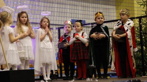Przedszkolaki występujące na scenie w hali sportowej z jasełkami podczas Wigilii dla Samotnych w Pleszewie.