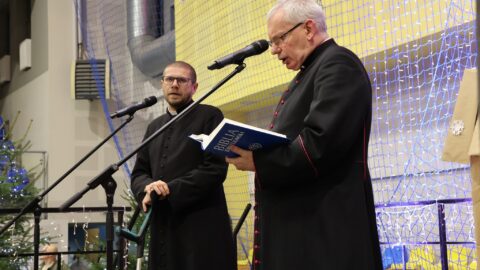 Przemówienie księży na scenie w hali sportowej podczas Wigilii dla Samotnych w Pleszewie.