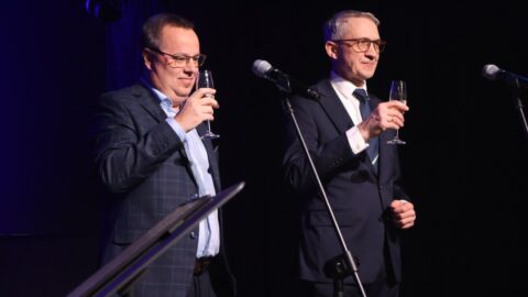 Władze miasta wznoszące toast na scenie podczas spotkania z organizacjami pozarządowymi.