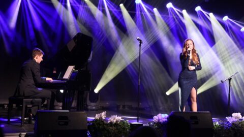 wokalistka oraz pianista występujący na scenie w blasku świateł.