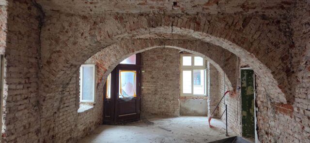 wnętrze remontowanej starej kamienicy z odkrytą starą cegłą na ścianach.